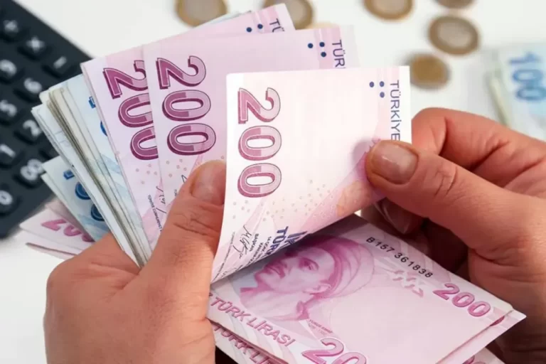 Elde tutulan 200 TL banknotlar ve arka planda hesap makinesi.