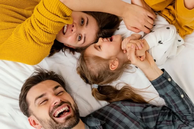 Prim iadeli hayat sigortası ile ailesini güvence altına alan, yatakta gülümseyerek yukarı bakan anne, baba ve çocuk.