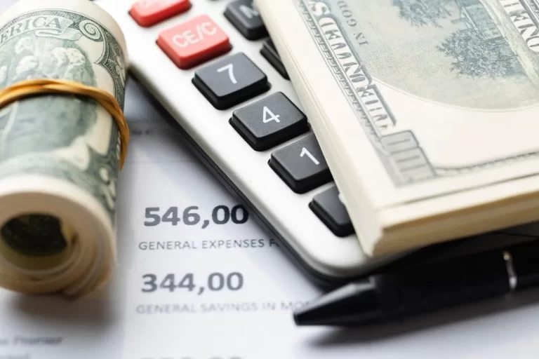 Hesap makinesi üzerinde lastikle rulo yapılmış dolar destesi