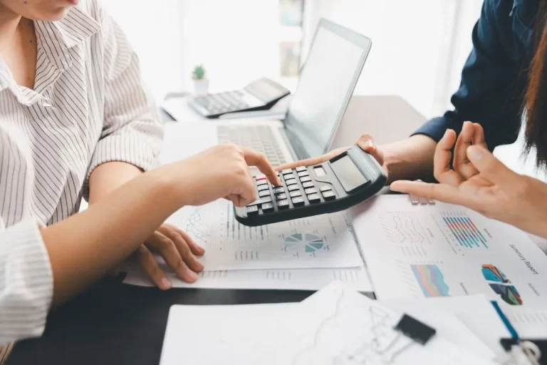 Ofis masasında hesap makinesi kullanarak BES fon yönetimi ve finansal hesaplamalar yapan profesyoneller.